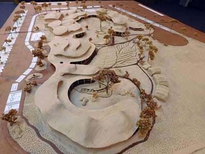 View of the model from the west side. In the foreground you can see the kindergarten classroom building. It is all U-shaped and open to the south. The overall shape thus creates a protected garden for kindergarten classes. This arrangement and shape took place through gradual participatory work together with teachers and parents.